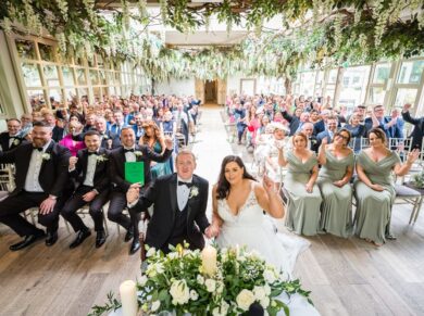 A bride and groom celebrate just after their wedding ceremony with all their guests sitting behind them