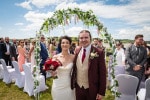 A bride and groom stand under a flower arch after their outdoor wedding ceremony at  Inchydoney Lodge and Spa