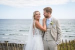 A bride and groom stand overlooking the sea on Inchydoney Island