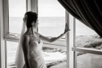 A bride looks out the window towards the sea from the bridal suite at  Inchydoney Lodge and Spa