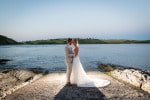 A bride and groom stand backlit in the evening on a jetty with the sea behind them at  Inchydoney Lodge and Spa