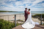 A bride and groom embrace on the viewing platform overlooking the sea at  Inchydoney Lodge and Spa, West Cork