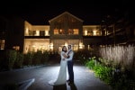 A bride and groom stand backlit at night outside bridesmaid in creative light at Inchydoney Lodge and Spa