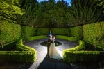 A bride and groom stand backlit in the garden of the Maryborough Hotel Cork