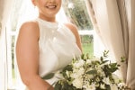 A bride holding her bouquet in front of a window