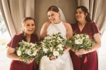 A bride and her bridesmaids laugh while holding their bouquets