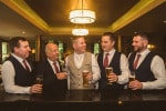 A groom and hiss groomsmen enjoy a drink in a bar