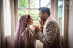 An Indian bride and groom embrace in front of a window at the Maryborough House Hotel in Cork, Ireland